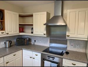 斯托诺韦Stornoway Holiday Let的厨房配有白色橱柜和炉灶烤箱。