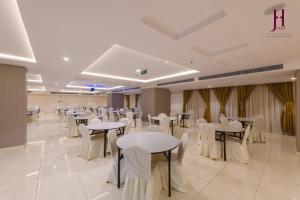 麦加Manazel Al Zaireen Hotel的宴会厅配有桌子和白色椅子