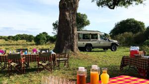 凯科罗克Muthu Keekorok Lodge, Maasai Mara, Narok的桌子、椅子和停在树旁的面包车