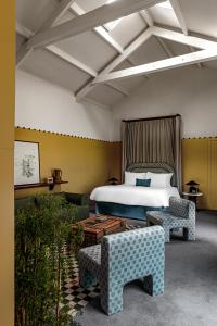 切尔滕纳姆Cowley Manor Experimental的一间卧室配有一张床、两把椅子和一张桌子