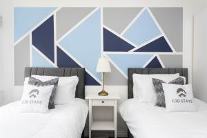 博勒姆伍德30 Percent Off Monthly Stays - Free Parking - Sky & Netflix的卧室设有2张床,拥有蓝色和白色的墙壁