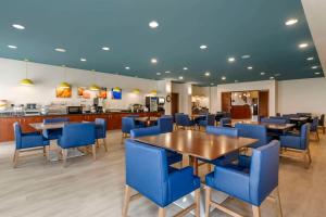 拉皮德城Comfort Suites Conference Center Rapid City的一间配备有蓝色椅子和桌子的用餐室
