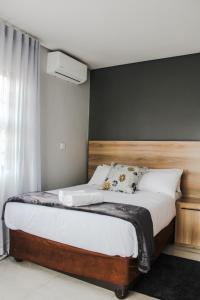哈博罗内The Rainbowtree B&B的一间卧室配有一张带木制床头板的床