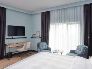 布达佩斯Radisson Hotel Budapest BudaPart的酒店客房配有一张床、两把椅子和一台电视