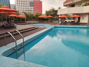 马尼拉The Heritage Hotel Manila的一个带橙色遮阳伞和桌椅的游泳池
