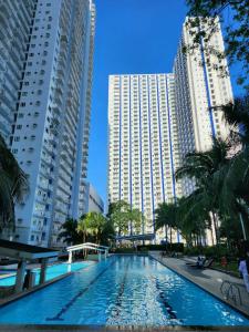 马尼拉High-Tech Studio at Grass Residences -2 persons only, Quezon City的两个高楼中间的一个游泳池