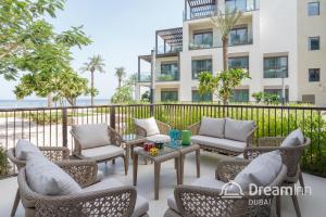 富查伊拉Dream Inn - Address Beach Residence Fujairah - Premium Apartments的大楼前带桌椅的天井