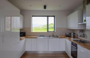 ElgolTaigh Druim的厨房配有白色橱柜和窗户。