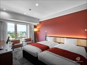 福山Daiwa Roynet Hotel Fukuyama Ekimae的红色墙壁的酒店客房内的两张床