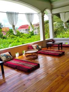 琅勃拉邦天堂鸟花园客栈的客厅铺有木地板,配有枕头。