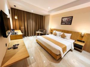 古瓦哈提Sachika Hotels, Guwahati的酒店客房设有一张大床和一张书桌。
