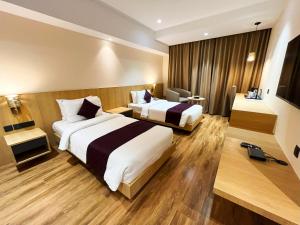 古瓦哈提Sachika Hotels, Guwahati的酒店客房设有两张床和电视。
