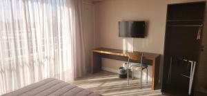 门多萨DAKAR HOTEL的一间卧室配有一张桌子,里面配有电视
