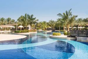 拉斯阿尔卡麦哈伊马角华尔道夫酒店的棕榈树和遮阳伞度假村的游泳池