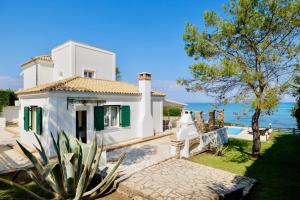 斯达林Beachfront Villa Dionysos - With private beach的白色的房子,设有绿色百叶窗,享有海景