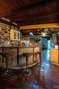 TriolloCasa rural la corva的厨房设有2个吧台凳和1面石墙