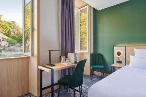 Évaux-les-BainsLe Grand Hôtel, The Originals Relais的酒店客房带一张床、一张桌子、一张床和窗户。