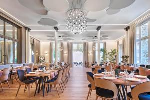 Évaux-les-BainsLe Grand Hôtel, The Originals Relais的餐厅设有木桌、椅子和吊灯。