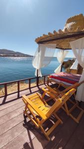 普诺Uros Utasa Lodge的两把躺椅和一把遮阳伞位于水边的甲板上