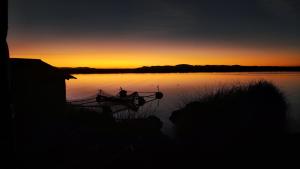 普诺Uros Utasa Lodge的日落时分坐在水面上的船