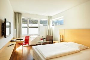 因斯布鲁克议会因斯布鲁克奥地利流行度假酒店的一间卧室配有一张床、一张桌子和一张桌子