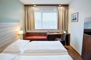 萨尔茨堡Austria Trend Hotel Salzburg Messe的酒店客房配有两张床和一张书桌