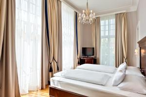 维也纳维也纳美泉宫奥地利时尚公园酒店的一间卧室配有两张床和吊灯。