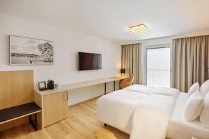维也纳Austria Trend Hotel Maximilian的酒店客房设有白色的床和电视。