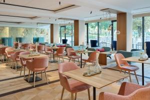 维也纳Austria Trend Hotel Maximilian的餐厅设有桌椅和窗户。