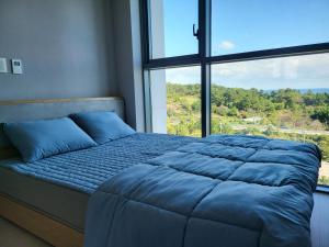 东海市KK Stay Ocean view with Netflix的窗户间内的一张带蓝色枕头的床