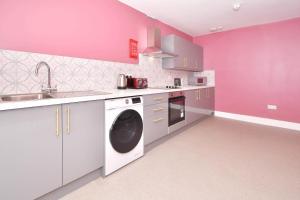 特伦特河畔斯托克One Battison - Affordable Rooms, Suites & Studios in Stoke on Trent的粉红色的厨房配有洗衣机和水槽