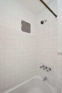 纽约Beautiful 2BR/1BA in Heart of NYC的白色的浴室设有浴缸和淋浴。