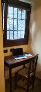 阿巴迪亚拉里亚纳La cascina della vigna del viandante的一张坐在木桌旁的笔记本电脑,窗户
