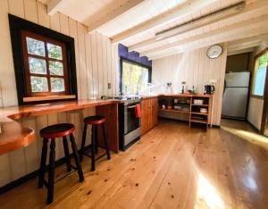 埃尔卡内洛Cabañas Casa en La Montaña的厨房铺有木地板,设有带凳子的柜台。
