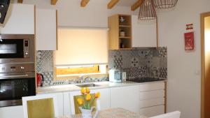 洛萨达Casa Ponte de Espindo的厨房配有白色橱柜和鲜花桌