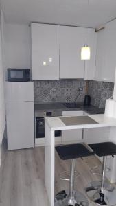 武科瓦尔Apartman Enio的厨房配有白色橱柜和桌椅