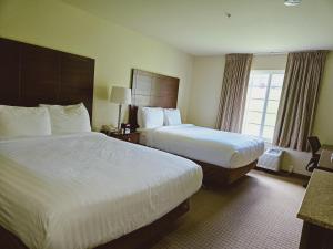 BloomfieldCobblestone Inn & Suites - Bloomfield的酒店客房设有两张床和窗户。