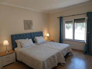 波塔莱格雷Herdade do Montinho的一间卧室配有一张带蓝色床头板的床和窗户