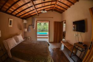 蒂拉登特斯Chalés da Estrada Velha的一间卧室设有一张床、一台电视和一个窗口。