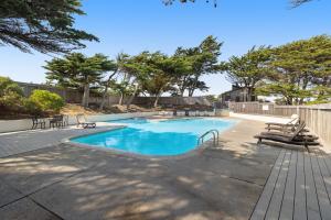 莫斯兰丁Monterey Dune Haven的庭院内一个带椅子和树木的游泳池