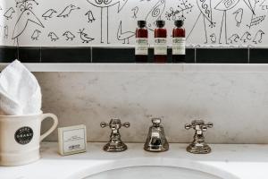 纽约苏豪区格兰德酒店的浴室水槽墙上有三瓶葡萄酒