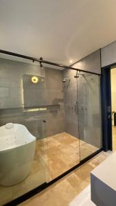 帕拉蒂Sandi Hotel的一间带玻璃淋浴和水槽的浴室