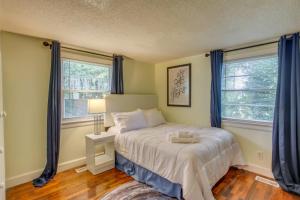 威尔明顿Mid-Century Wilmington Cottage 3 Mi to Riverwalk的一间卧室设有一张床和两个窗户。
