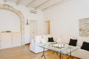 锡拉库扎B&B Palazzo Del Sale的客厅配有白色沙发和玻璃桌