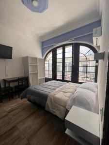 蒙得维的亚Nuevo Hotel Aramaya的一间卧室配有一张大床、大窗户和一张书桌