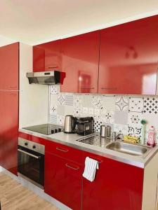 圣吉欧梅斯Appartement Ensoleillé à 15 minutes de Paris的红色的厨房,配有水槽和红色橱柜