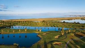 吉亚Herdade dos Salgados, Beach Villa, 3 Suites的享有棕榈树和水的高尔夫球场的空中景致