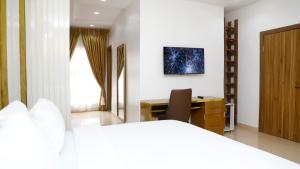 拉各斯Delight Apartments - Oniru VI的一间卧室配有一张床、一张桌子和一把椅子