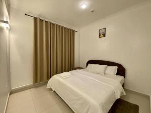 达累斯萨拉姆Homely 2-Bedroom at Victoria Place的一间卧室配有一张带白色床单的床和一扇窗户。