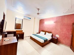 新德里Ashoka International Hotel - Karol Bagh New Delhi的一间卧室配有一张床、一张书桌和一台电视
